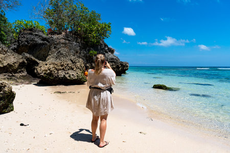 Uluwatu, Bali, Indonesia - September 01, 2025: Rear view of a tourist taking photo in Padang Padang Beach Bali, Indonesia.のeditorial素材