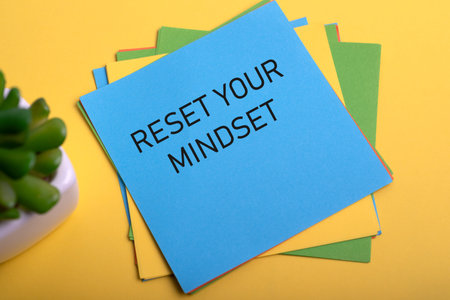 Adhesive note with text Reset Your Mind on yellow backgroundの写真素材