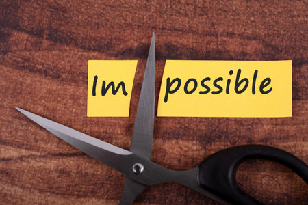 Scissors cutting the word impossible to possible