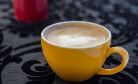 Cappuccino coffee on black ornament tableclothの写真素材