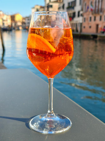 A glass of Aperol spritz cocktail on the table of a Venetian cafe. Venetian background.の写真素材
