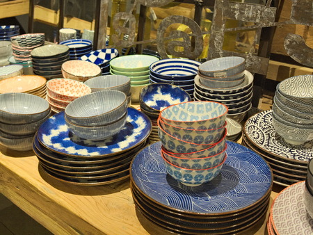 Multicolour blue cups and plates with ornament on yellow table in dishware shop