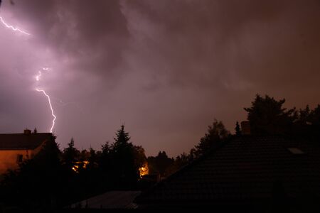 A lightning going from cloud to ground during a summer thunderstorm at night