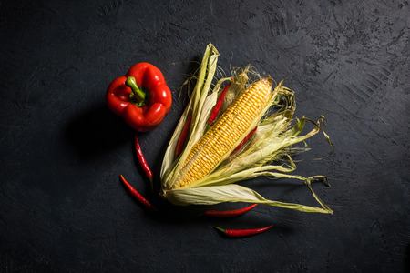 Corncob with pepper on a black stone backgroundの写真素材