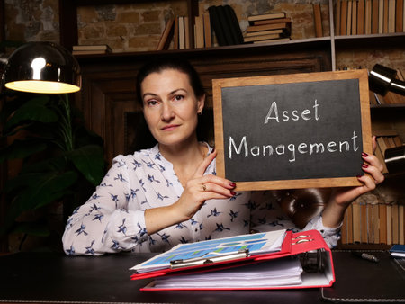 A handsome businesswoman showing a black piece of paper with sign Asset Management . Close-up shot. Soft focus.の写真素材