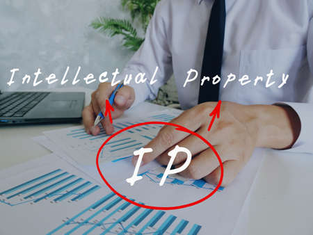 Conceptual photo about IP Intellectual Property with handwritten acronym.Man signing document on background.の写真素材