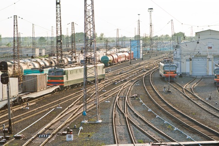 Cars and electric locomotives on tracks in sunset sunlight