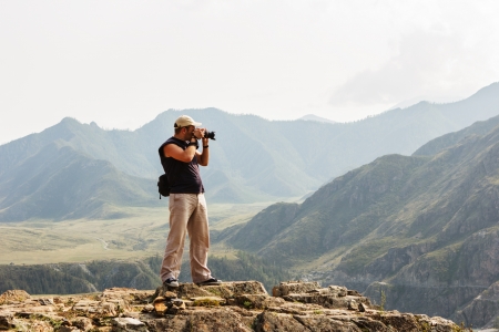 Beautiful landscape with the silhouette of photographer on background of mountainsの写真素材