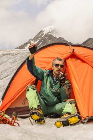 The climber sits in tent and causes the help highly in mountainsの写真素材