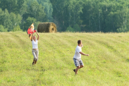 Happy couple man and woman outdoors fly a kite の写真素材