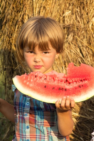 Portrait with mimicry of the child at foods of sweet water-melonの写真素材