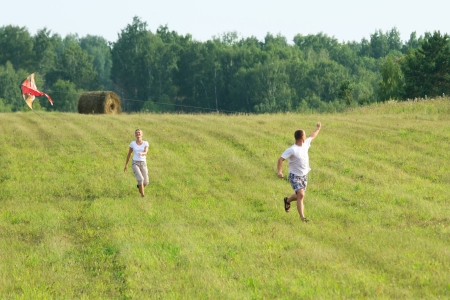 Couple of young people run with kite in hands.の写真素材