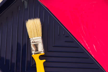 Red paint with yellow brush in tray. Top view.の写真素材