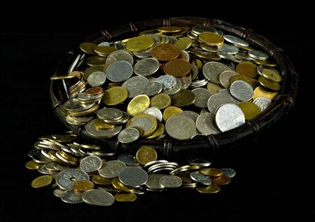 Various coins in a basket on black backgroundの写真素材