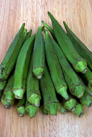 A group of Okra laid out in a group on a chopping board.