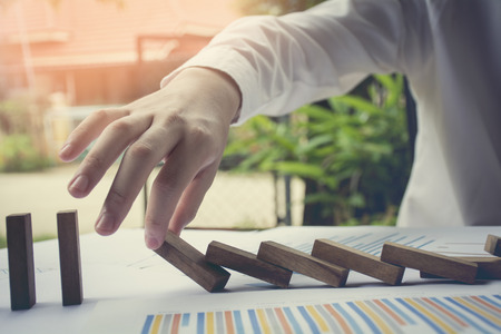 Problem Solving Close up  on hand of business stopping falling blocks on table for concept about taking responsibility.の写真素材