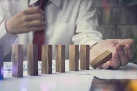 Problem Solving Close up  on hand of business stopping falling blocks on table for concept about taking responsibility.の写真素材