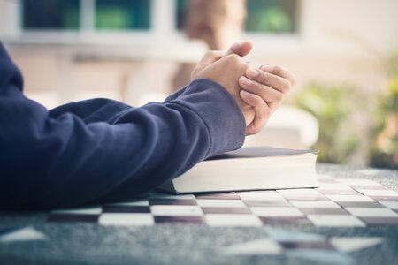 man holding a bible in her hands and prayingの写真素材