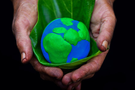 Human hands holding global over blurred green nature background. Sustain earth concept. Love nature. Save the planet.の写真素材