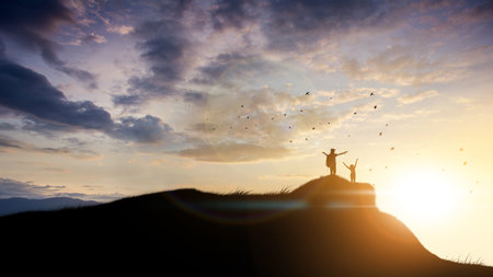 Happy cheering celebrating success woman at beautiful sunset above the clouds. Girl enjoying view of colorful sunset with arms raised up towards the sky.の写真素材