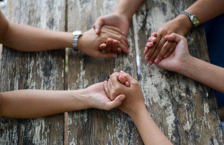 Group of people Praying Hands Over The Bible On Wooden Deskの写真素材