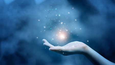 Religion and belief in God on blessing background. Power of hope or love and devotion. Magic powder floating on the magician hand.の写真素材