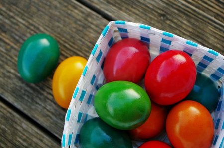 Dyed colorful easter eggs in egg basket on wooden background for easter celebrationの素材