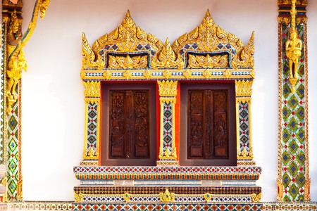 Two craved windows with mosaic frame in buddist templeの写真素材