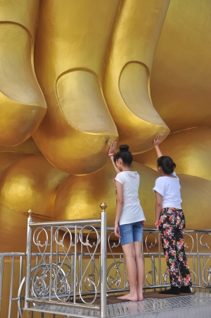 Two Thai woman pay respect a Golden Buddha statue at Wat Muang temple in Angthong Thailandの写真素材