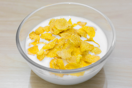 bowl of corn flakes and spoon on wood background.の写真素材