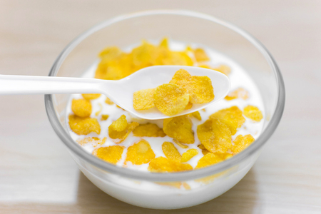 bowl of corn flakes and spoon on wood background.の写真素材