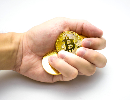 Golden bitcoins in hand. Digital symbol of a new virtual currency on white background.の写真素材