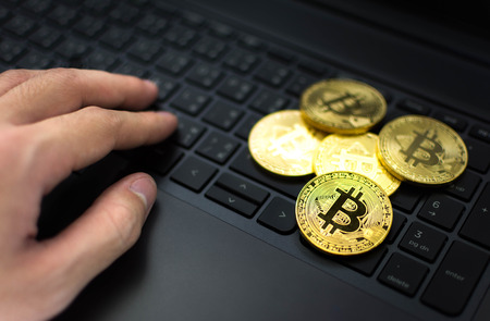 Golden Bitcoins and hand on computer keyboard background.の写真素材