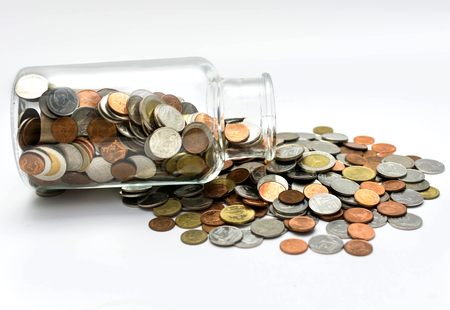 Thai bath coins spilling out of a glass jar.の写真素材