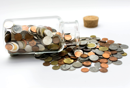 Thai bath coins spilling out of a glass jar.の写真素材