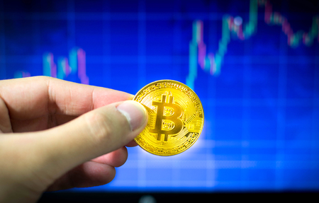 Man holding gold bitcoin and BTC trading chart in background, Financial conceptの写真素材