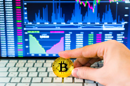Hand hold gold bitcoin and trading chart background. Virtual currency concept.の写真素材