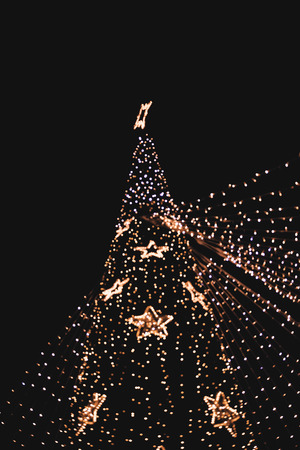 Low Angle View Of Slightly Defocused Lights On Christmas Tree During Nightの写真素材