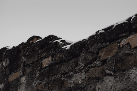 Low Angle View Of Snow-Covered Brick Wall Against Moody Sky During Winter Snowの写真素材