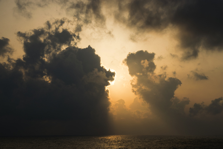 Bright Sun Shining Through Dark Clouds On The Seaの写真素材