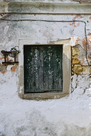 Old Wooden Greek Traditional Window With Green Paint And Ripped Pieces Of Paper On Crumbling Facadeの写真素材