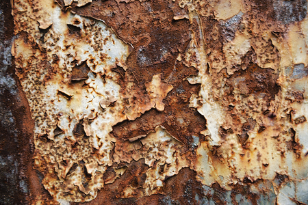 Close-Up Of Crumbling White Paint Peeling Off From A Rusty Metal Wall