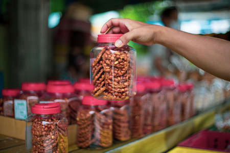 Thai fried peanut cookies are in a jar for sale at the ancient floating market in Thailand.の写真素材