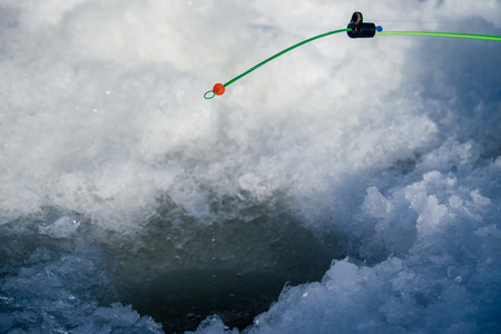 Fishing rod for winter fishing in the snow in the holeの写真素材