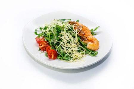 Shrimp with tomato, greens and cheese on a plate and a white backgroundの写真素材