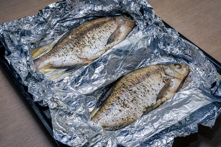 Fish baked in foil close-up lies on a trayの写真素材