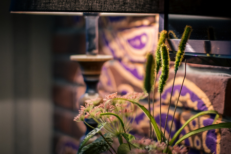 Flowers in a cafe near a brick wall and with a table lamp