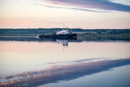 Tug pulls a barge on the river Severnaya Dvinaの写真素材
