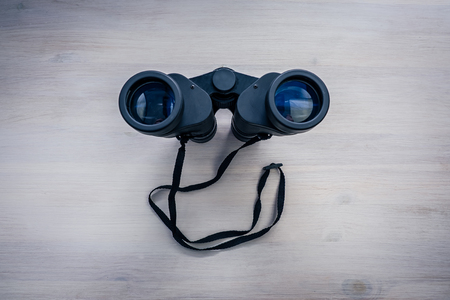 Black binoculars on a wooden tableの写真素材