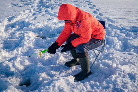 A girl on winter fishing is fishing on the lakeの写真素材
